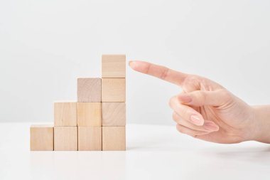 Tahta yapı taşları merdiven şeklinde dizilmiş ve bir kadının eli işaret ediyor.