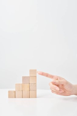 Tahta yapı taşları merdiven şeklinde dizilmiş ve bir kadının eli işaret ediyor.