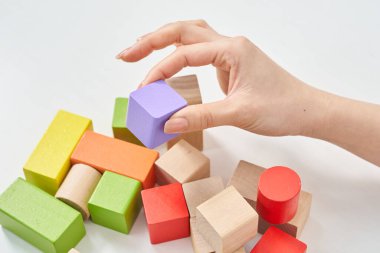 Tahta blokları ve beyaz arka planı olan bir kadının elleri.