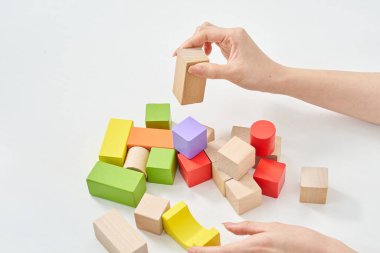 Tahta blokları ve beyaz arka planı olan bir kadının elleri.