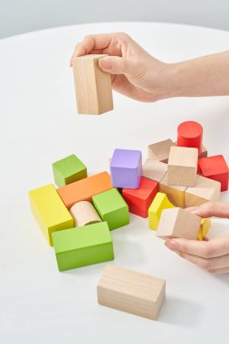 Tahta blokları ve beyaz arka planı olan bir kadının elleri.