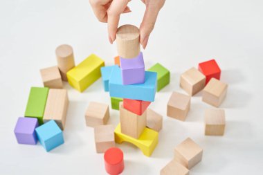 Tahta blokları ve beyaz arka planı olan bir kadının elleri.