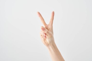 V işaretini ve beyaz arkaplanı oluşturan bir elin yakın çekimi