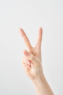 V işaretini ve beyaz arkaplanı oluşturan bir elin yakın çekimi