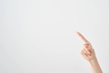 Bir kadının işaret parmağı çapraz olarak yukarı ve beyaz arkaplanı gösteriyor