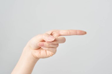 Kadın işaret parmağı yan ve beyaz arkaplanı gösteriyor