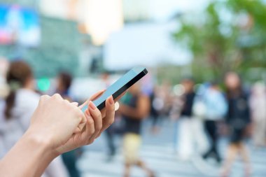 Şehir merkezinde akıllı telefon kullanan bir kadının eli.
