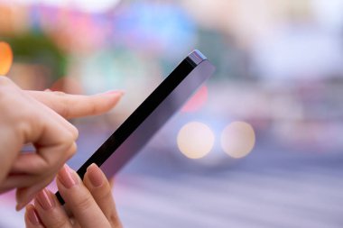 Şehir merkezinde akıllı telefon kullanan bir kadının eli.