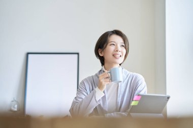 Orta yaşlı bir kadın bir kupayla işe ara veriyor.