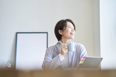 Orta yaşlı bir kadın bir kupayla işe ara veriyor.