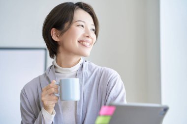 Orta yaşlı bir kadın bir kupayla işe ara veriyor.