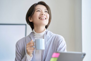 Orta yaşlı bir kadın bir kupayla işe ara veriyor.