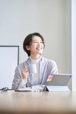 Orta yaşlı bir kadın bir kupayla işe ara veriyor.