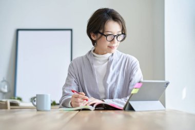 Orta yaşlı bir kadın bir odada çalışıyor.