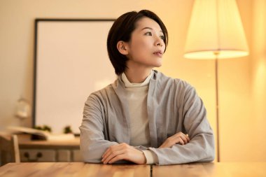 İç mekan aydınlatmalı bir odada rahat bir ifadeye sahip orta yaşlı bir kadın.