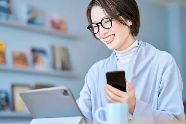 stock image A woman operating a tablet PC and smartphone in the room