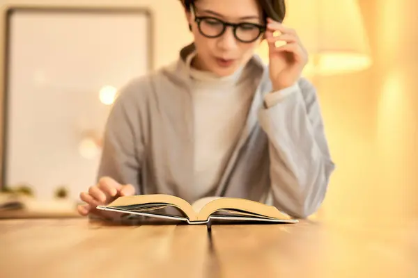 stock image A woman reading in a room with warm lighting