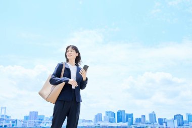 Elinde akıllı bir telefonla işe giden genç bir kadın.