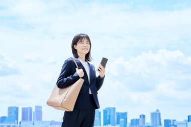 Elinde akıllı bir telefonla işe giden genç bir kadın.