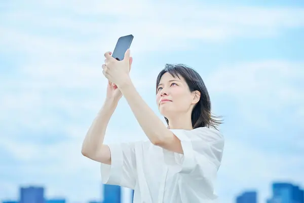 Stock image A young woman operating a smartphone outdoors