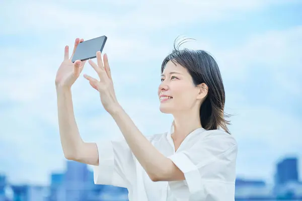 stock image Young woman looking at smartphone screen outdoors