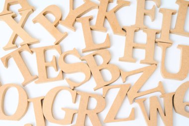 Ahşap alfabe blokları karışık ve beyaz bir arkaplanda sıralanmış