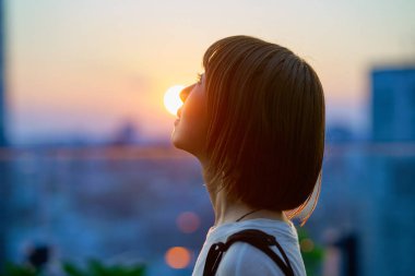 Sihirli bir saatte şehirde duran genç bir kadının portresi.