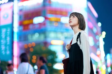 Genç bir kadın gece şehir merkezine bakıyor.