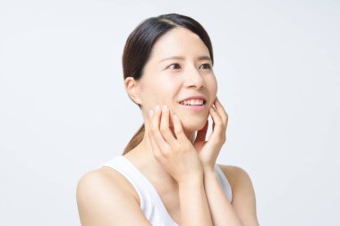 Kolsuz tişörtlü bir kadın cilt durumunu kontrol ediyor.