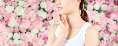 Kadının elleri yüzüne ve çiçek arkaplanına dokunuyor