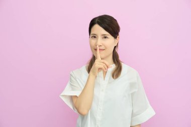 A young woman posing indoors with her index finger over her mouth clipart