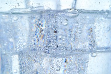 Buzlu ve beyaz zeminli bir bardakta karbonatlı su.