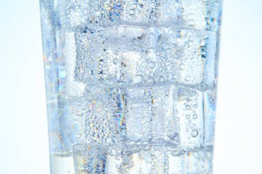 Buzlu ve beyaz zeminli bir bardakta karbonatlı su.