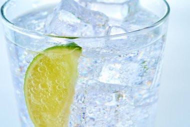 Glass of carbonated water with ice and lime clipart