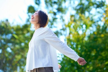 Güneşli bir günde yeşillikte gülümseyen bir kadın.