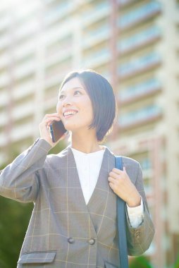 İş kadını güzel bir günde elinde akıllı bir telefon tutuyor.