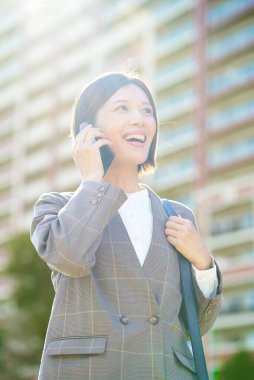 İş kadını güzel bir günde elinde akıllı bir telefon tutuyor.