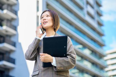 İş kadını güzel bir günde elinde akıllı bir telefon tutuyor.