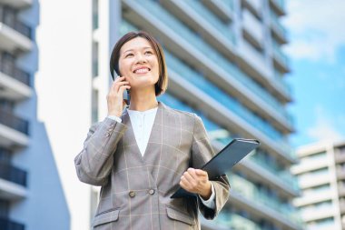 İş kadını güzel bir günde elinde akıllı bir telefon tutuyor.
