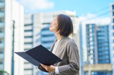 İş kadını güzel bir günde apartmanın önünde duruyor.