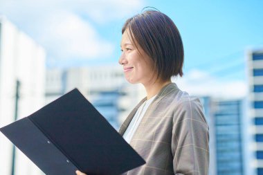 İş kadını güzel bir günde apartmanın önünde duruyor.