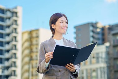 İş kadını güzel bir günde apartmanın önünde duruyor.