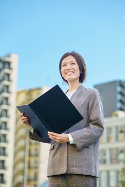 İş kadını güzel bir günde apartmanın önünde duruyor.