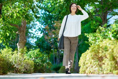 Woman walking in green space on fine day clipart