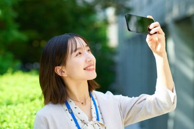 Genç iş kadını dışarıda akıllı telefonu tutuyor.