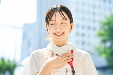 A woman in a white coat posing with a smile outdoors clipart