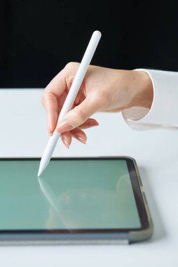 Stüdyoda bir stil kalemi tutuyor.