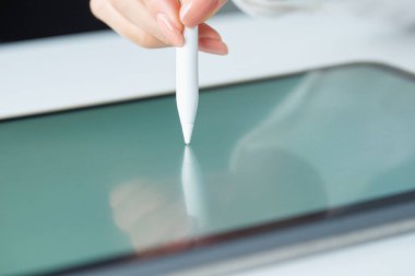 Stüdyoda bir stil kalemi tutuyor.