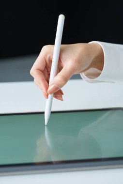 Stüdyoda bir stil kalemi tutuyor.