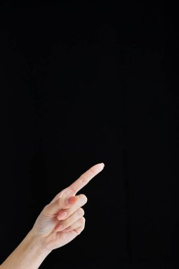 İşaret parmağıyla siyah arka plan stüdyosunu işaret ederek.